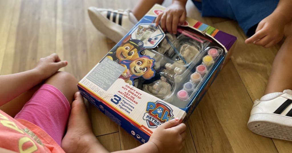 boy and girl on floor holding craft kit