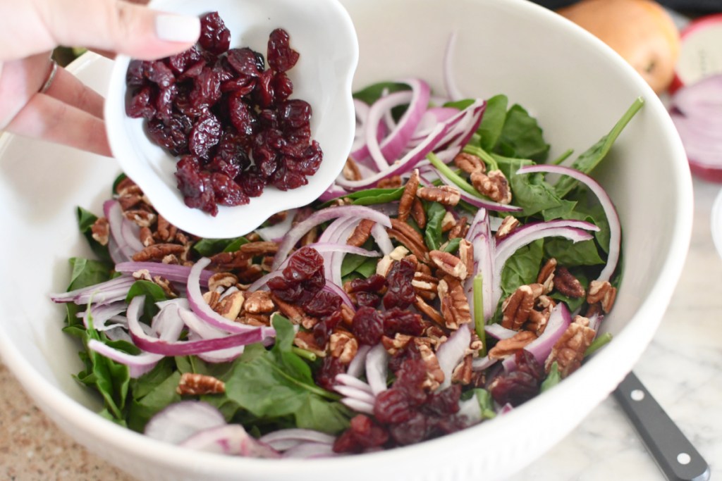 adding dried cherries to spinach salad