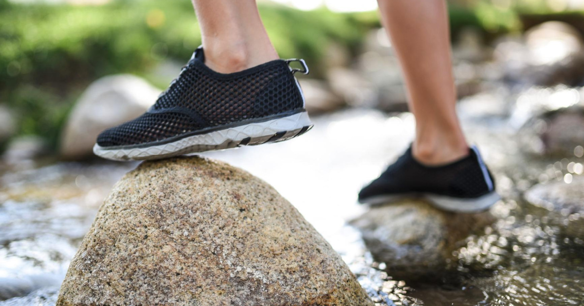 child stepping on rock in water shoes