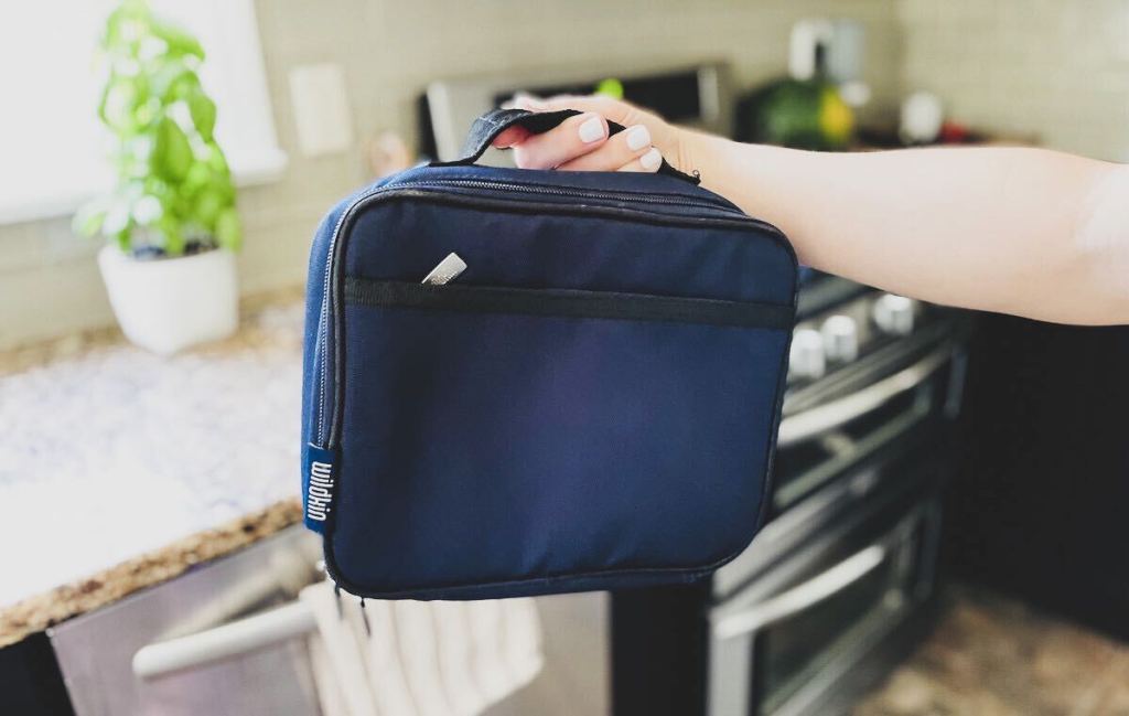 hand holding up navy blue lunchbox in kitchen