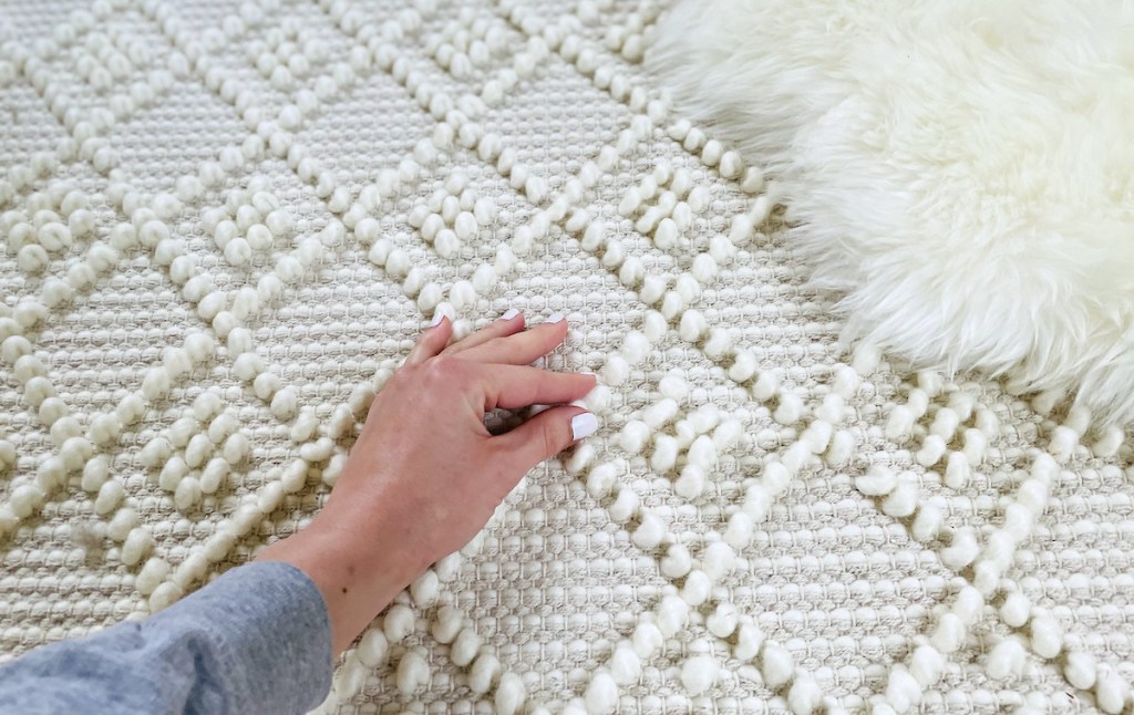 hand touching surface of knotted boho cream rug