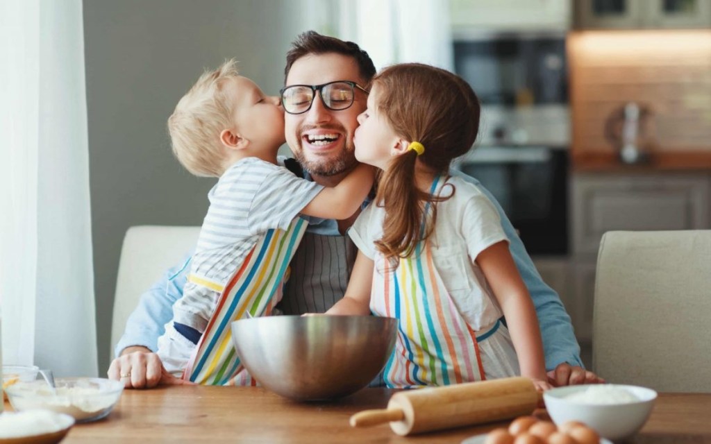 two kids kissing man on cheek