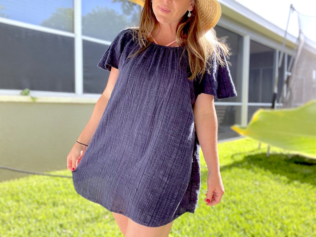 woman wearing navy blue swimsuit cover up with beach hat
