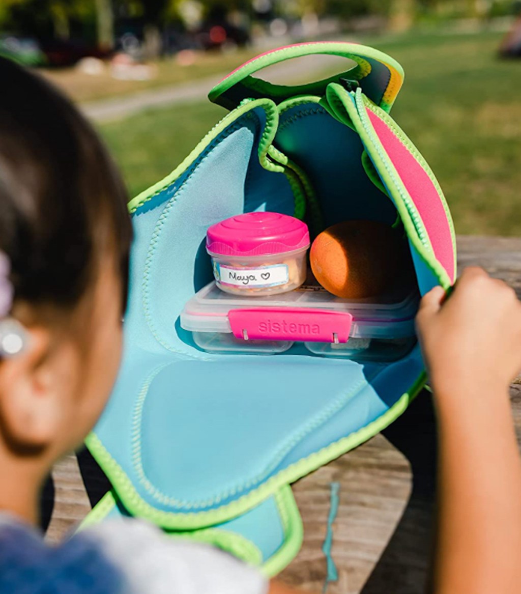 child peeking into open lunchbox