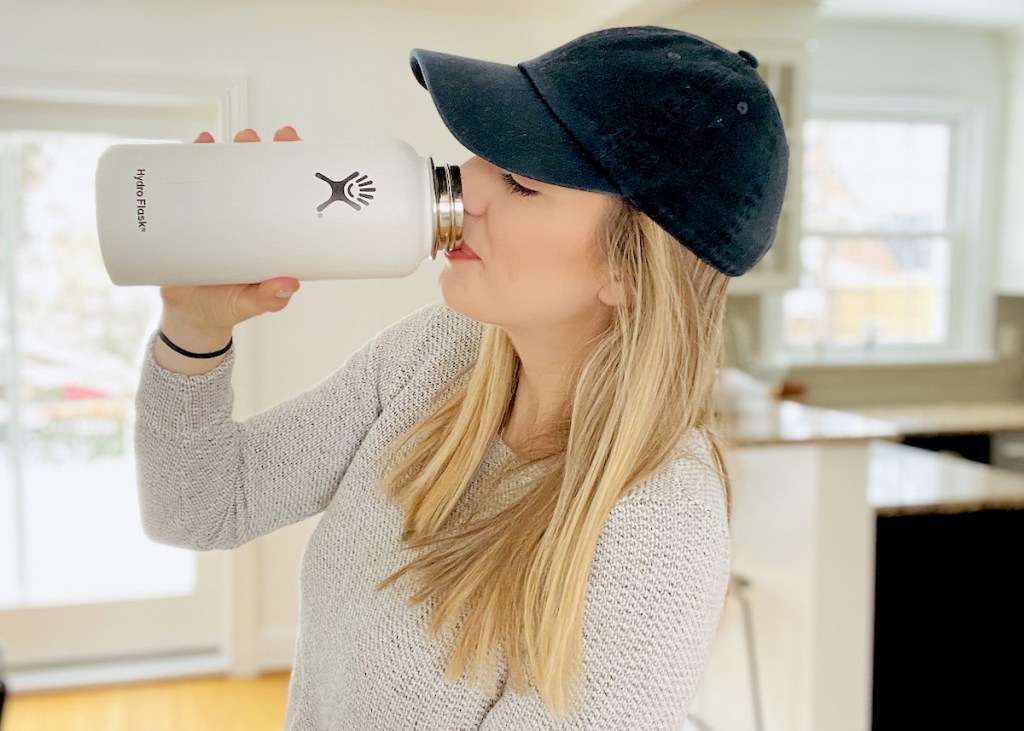 woman drinking out of white hydroflask water bottle