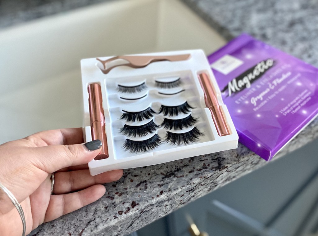 hand holding a box of false lashes in bathroom