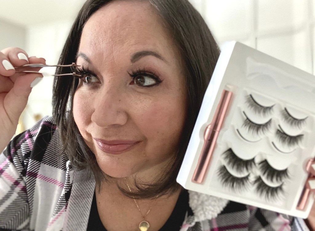 woman holding up tweezers to eye looking in mirror