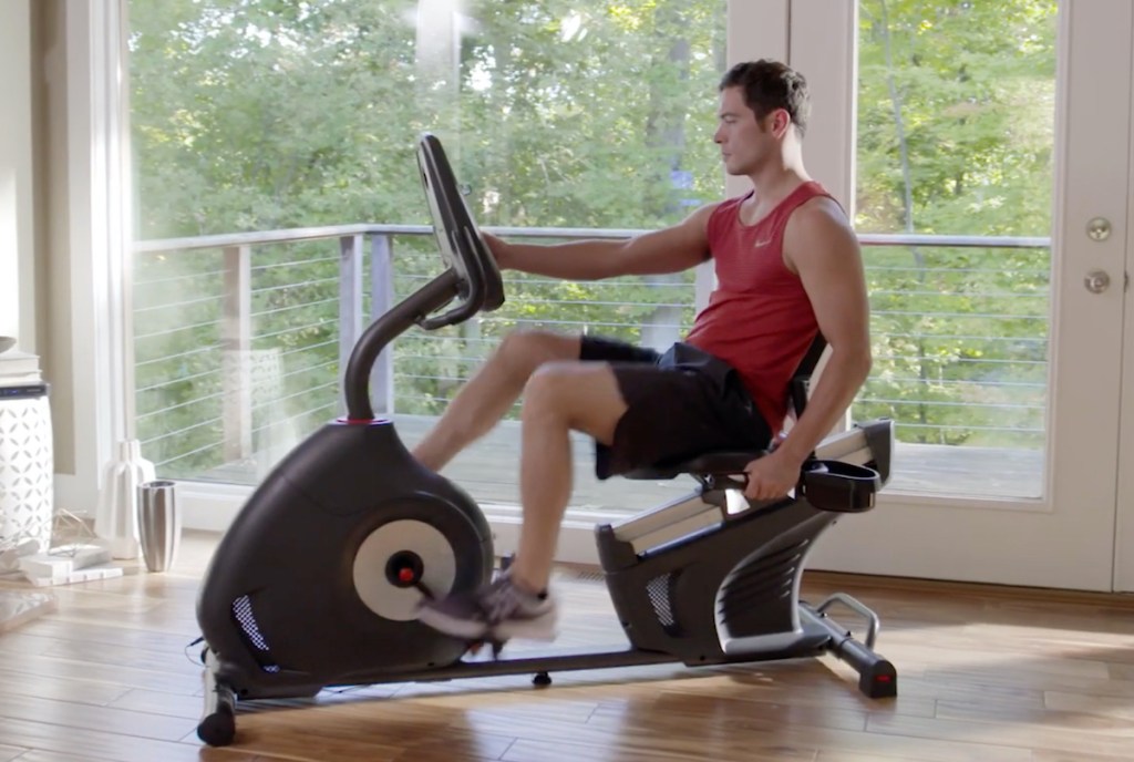 man sitting on exercise bike in room full of windows