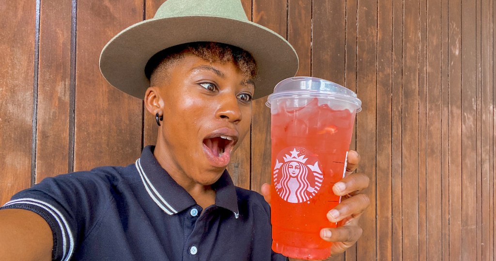 woman with mouth open staring at pink drink in starbucks cup