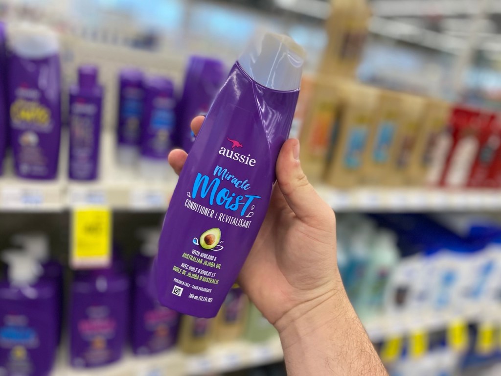 hand holding purple bottle of conditioner 
