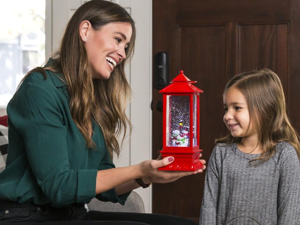 woman holding snow globe next to little girl
