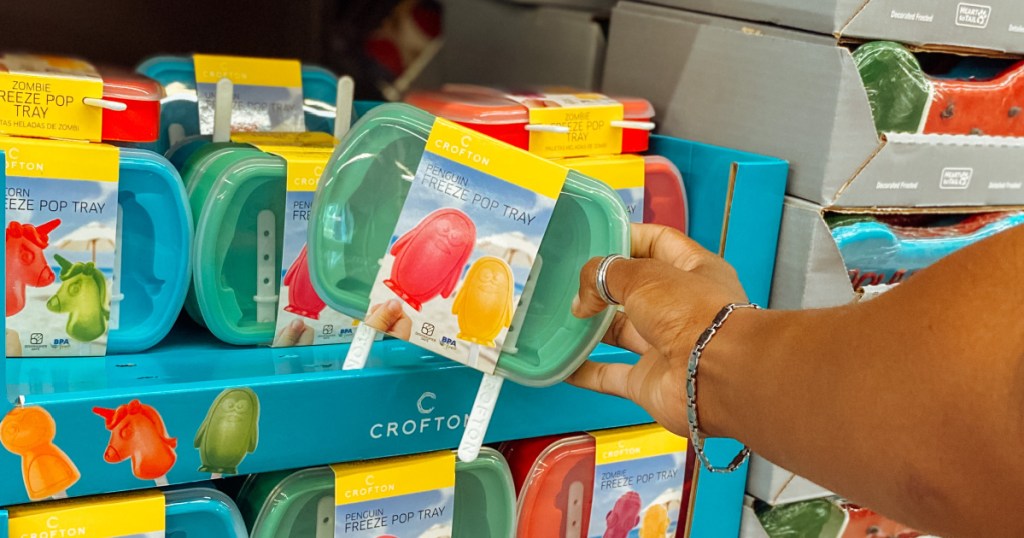 hand holding package of penguin popsicle molds near in-store display