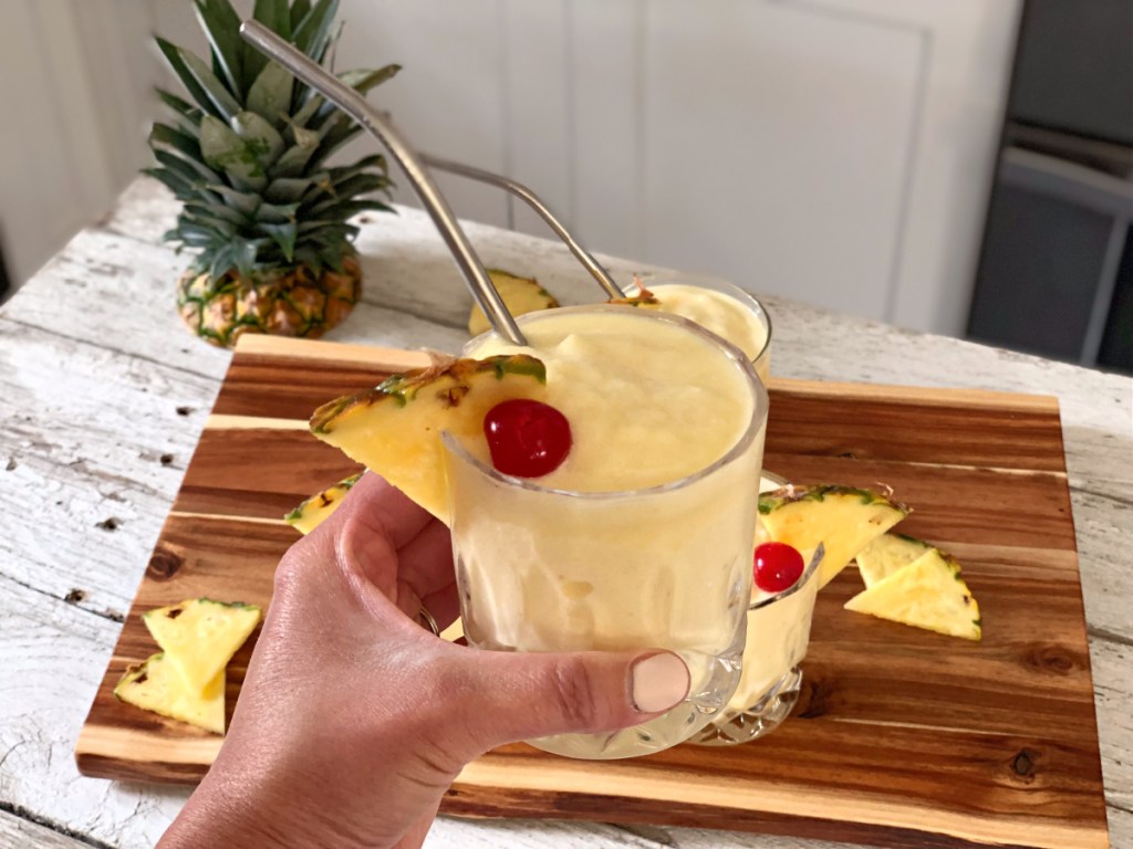 holding a glass of the best Piña Colada recipe