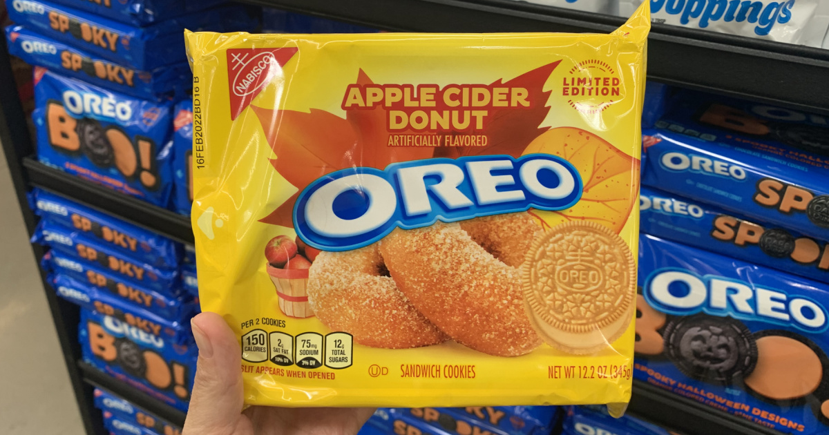 hand holding a package of apple cider donut oreos in front of a store display