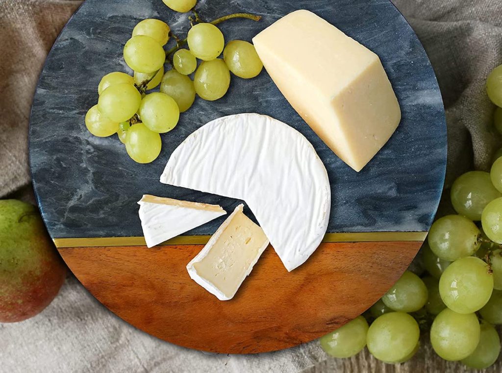 black marble serving board with green grapes and cheese on top