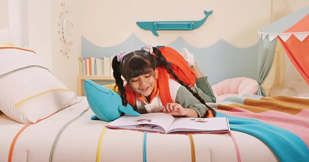 girl reading book on colorful bedding