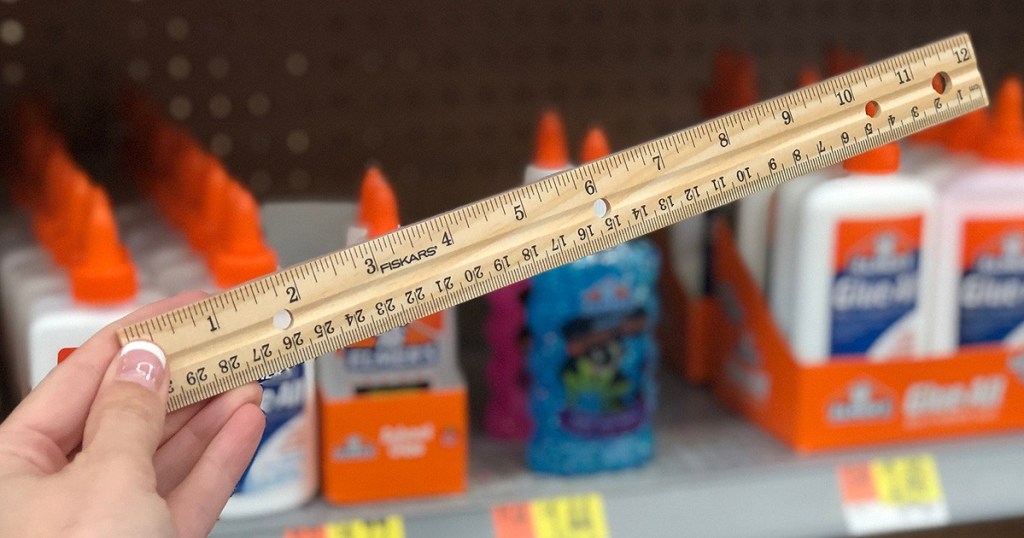 holding a wooden ruler at Walmart