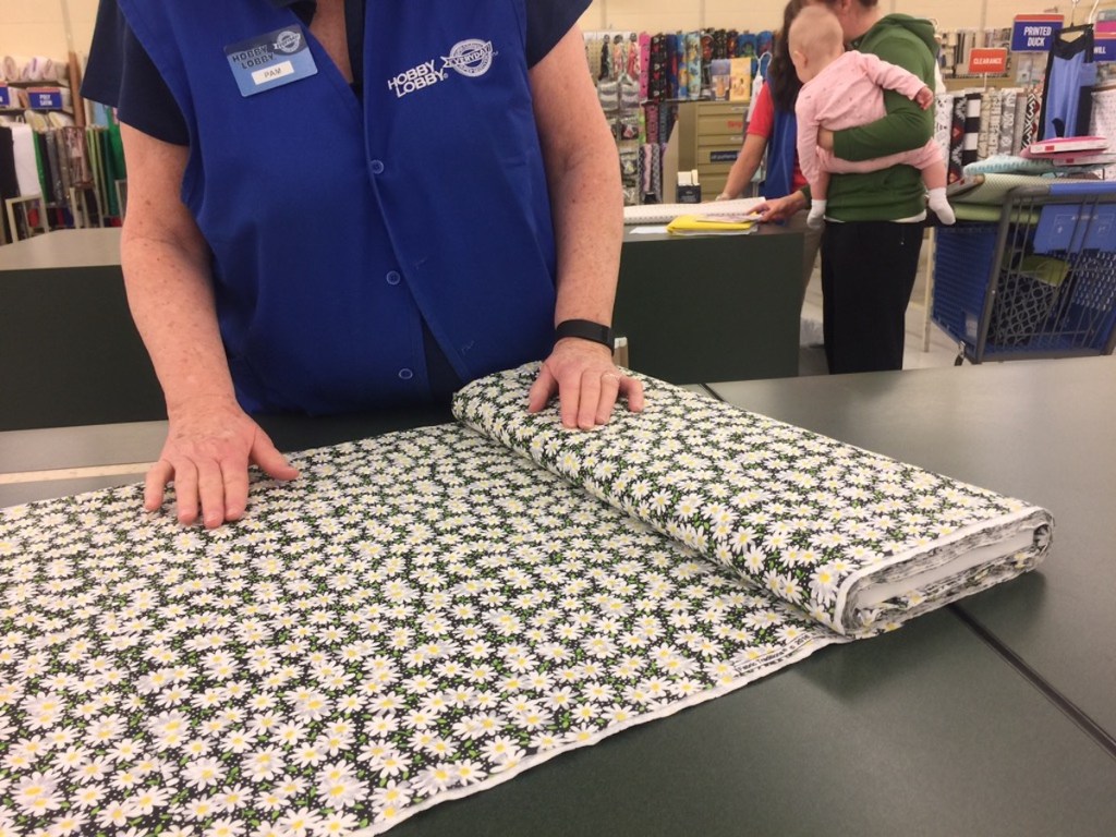 woman rolling out floral fabric on hobby lobby countertop