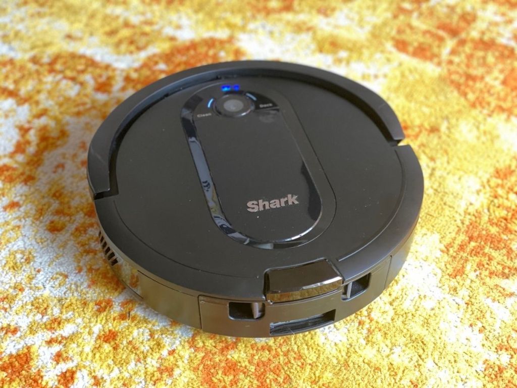 Shark robot vacuum on yellow and orange rug