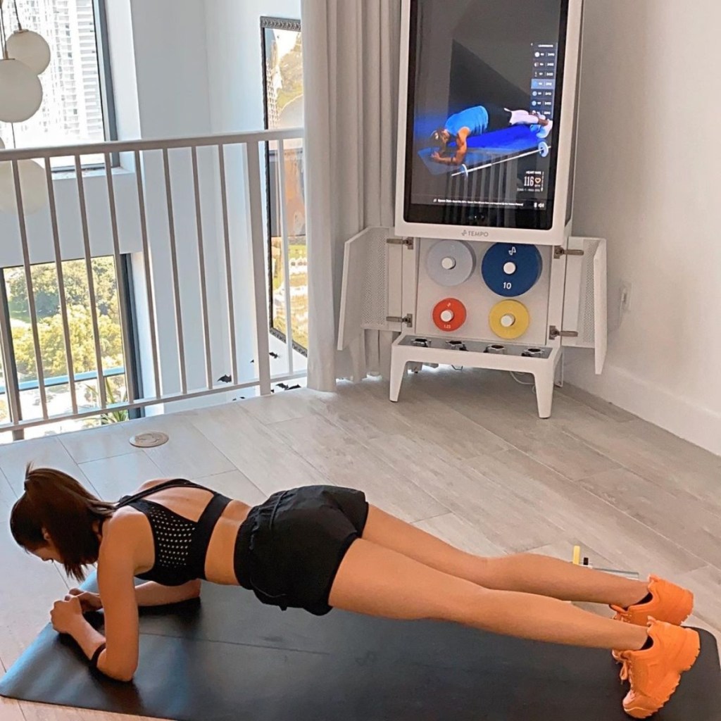 woman doing plank on black exercise mat