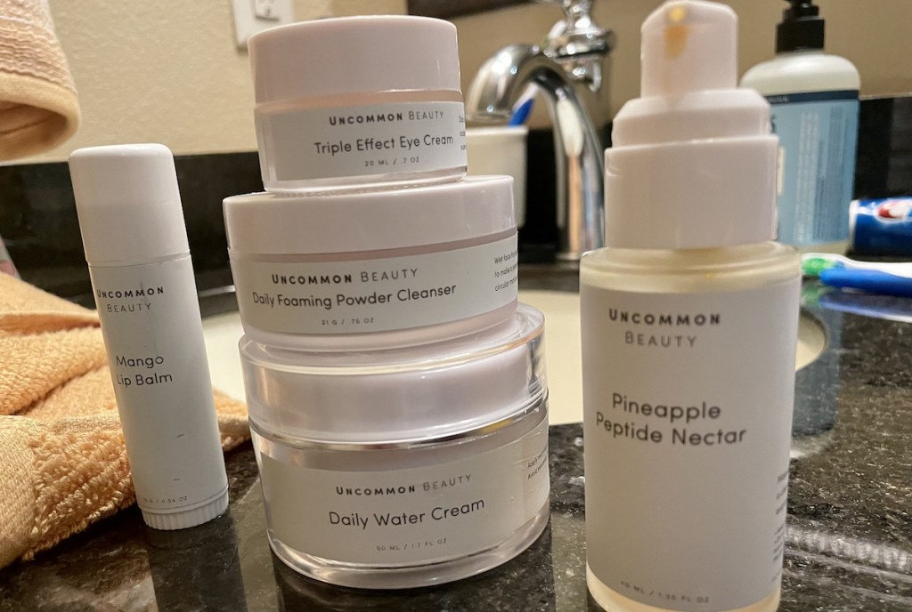 stack of uncommon james skincare products and vitamin c serum on bathroom counter