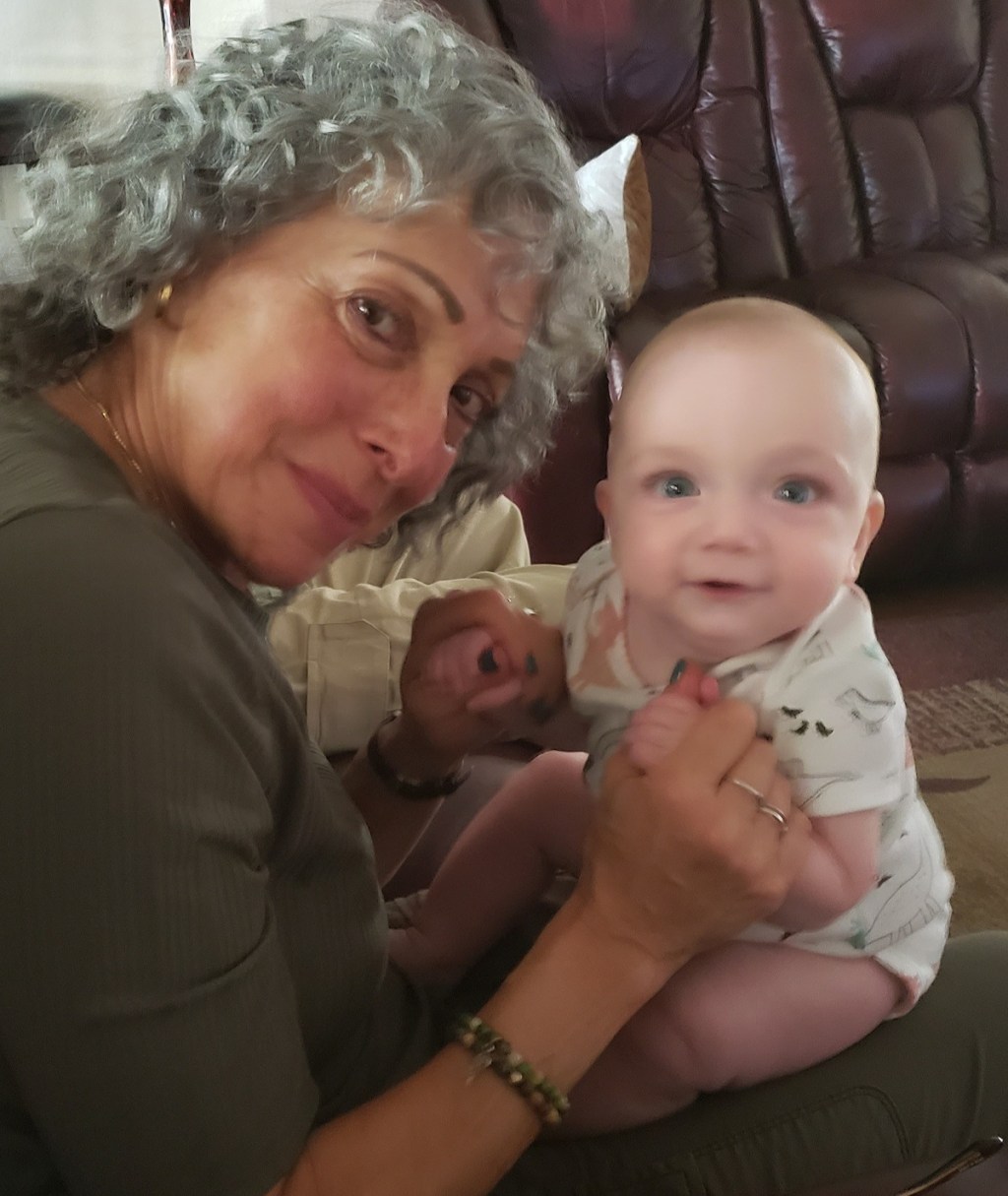 woman with baby on lap sitting on couch looking at camera