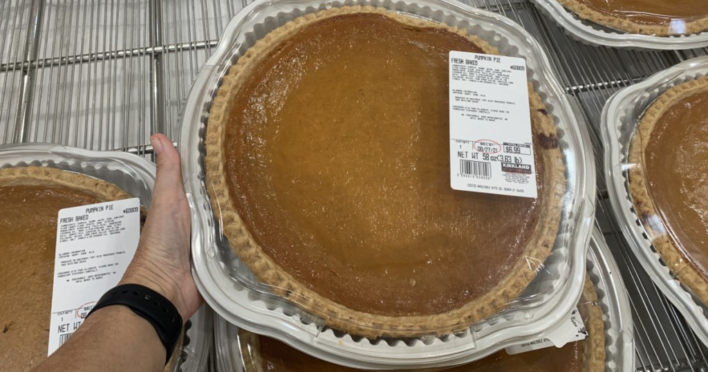 extra large pumpkin pie in hand near shopping cart