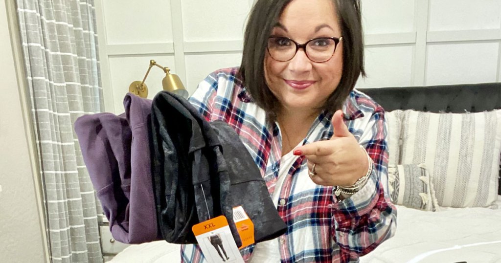 woman holding up and pointing to pairs of leggings