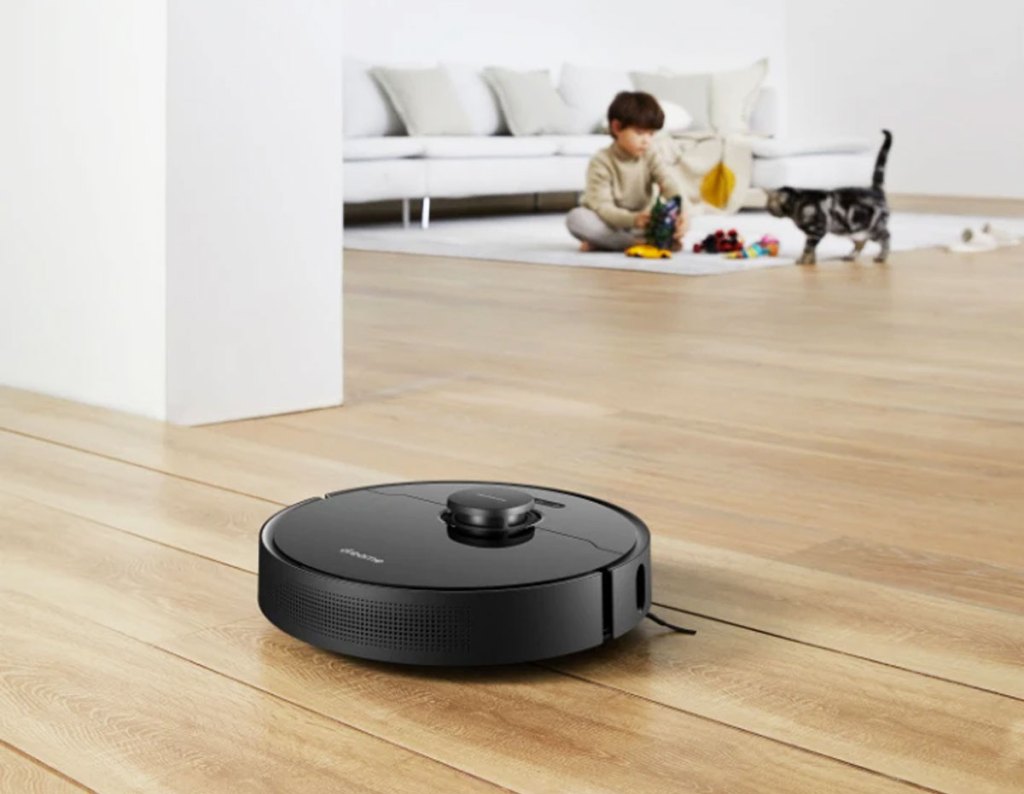 black vacuum on wood floor with cat and boy in background