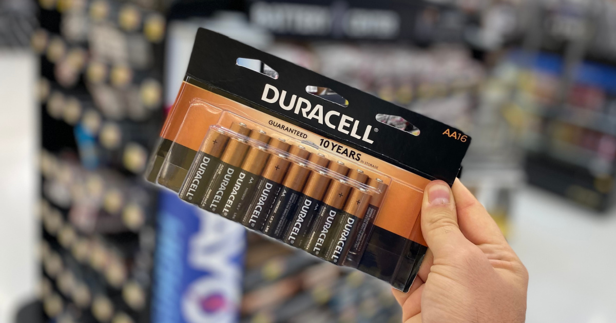 hand holding up a large multipack of duracell batteries in front of a battery store display