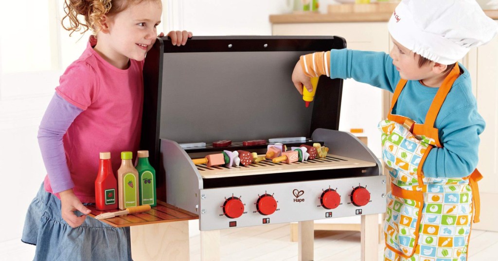 2 children standing next to a wooden hape grill