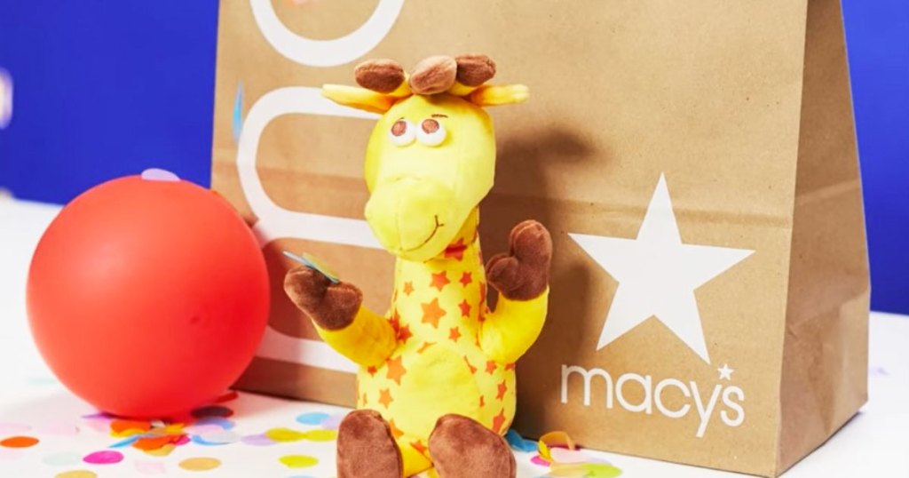 Geoffrey Giraffe stuffed animal next to Macy's bag