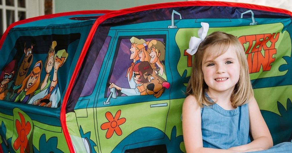 girl sitting next to a play tent