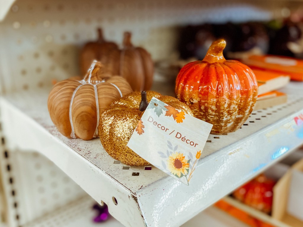 three small decorative pumpkins on shelf in store