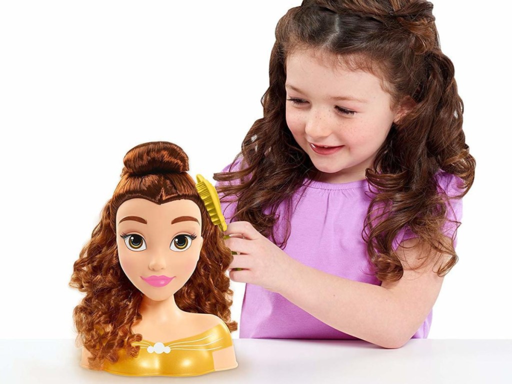 little girl playing with disney belle doll head 