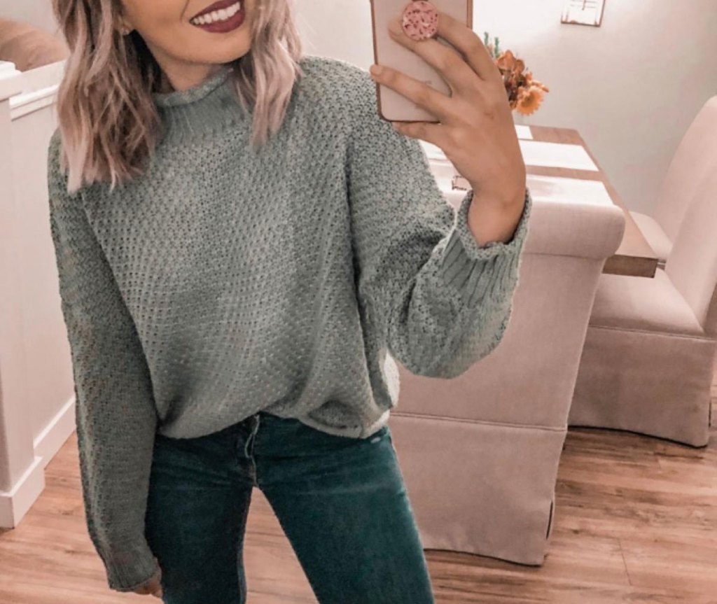 woman in gray sweater taking selfie