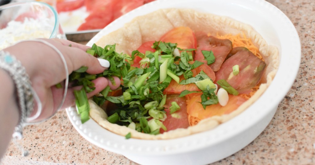 adding basil and onion to tomato pie