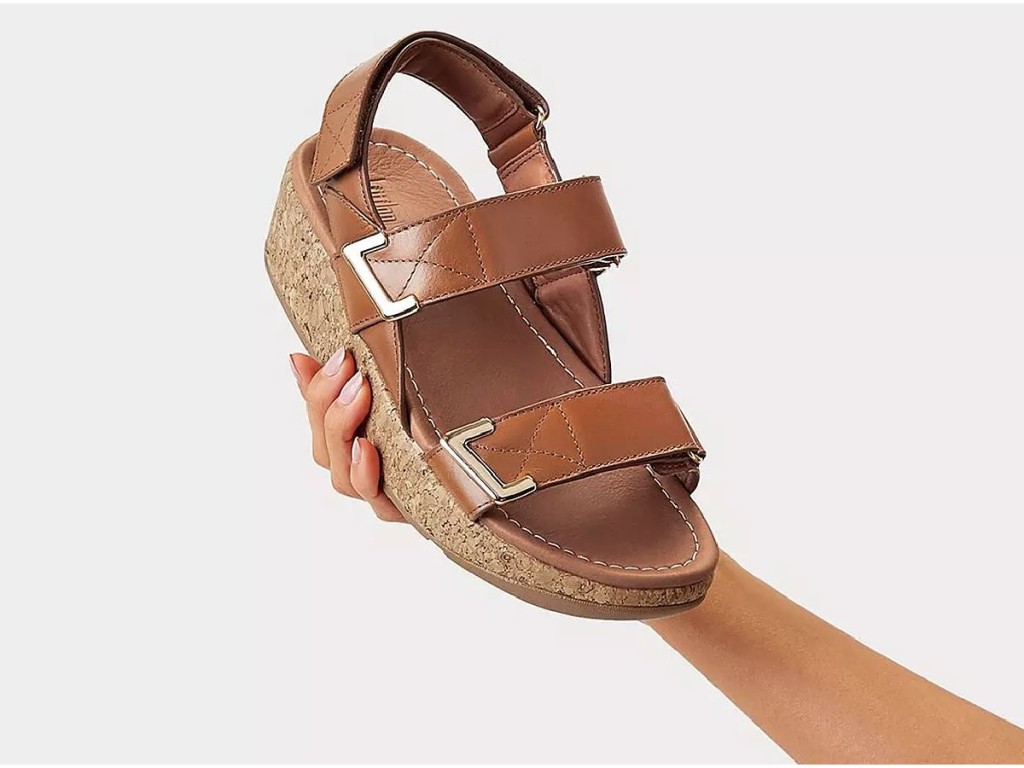 hand holding up brown sandal