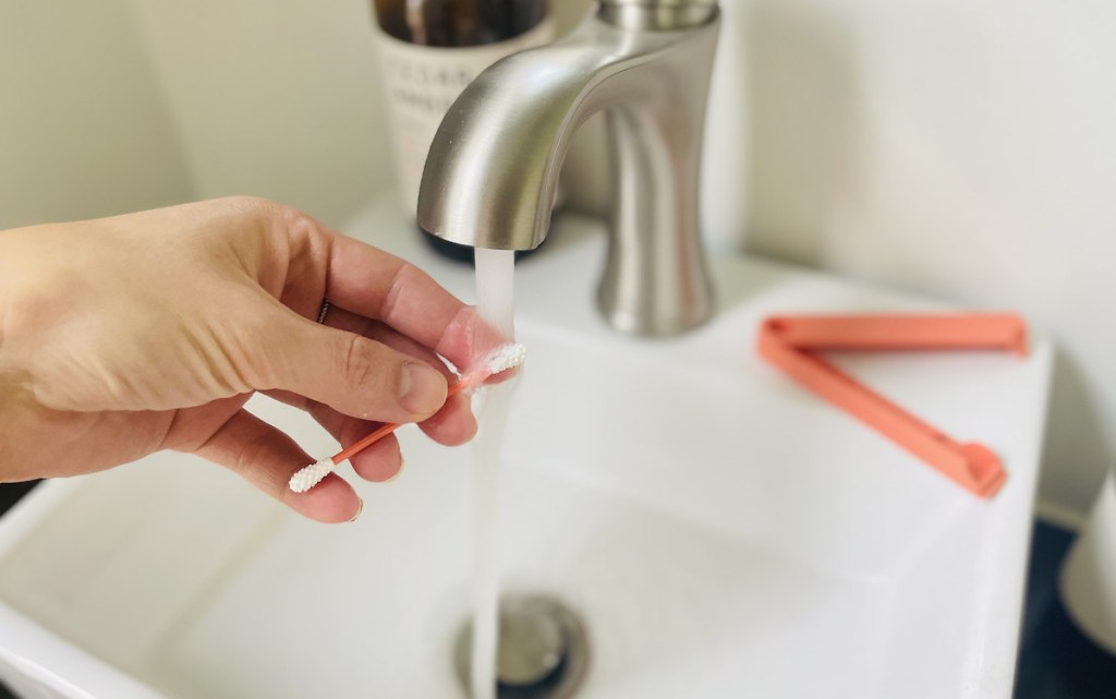 hand holding reusable q tip under bathroom sink