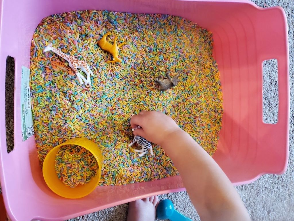 pink bin filled with colored rice and toys