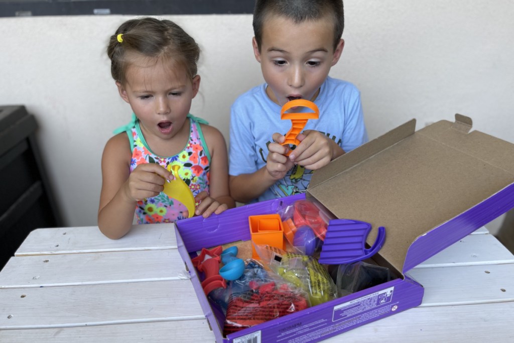 kids playing with kinetic sand w/ surprised face