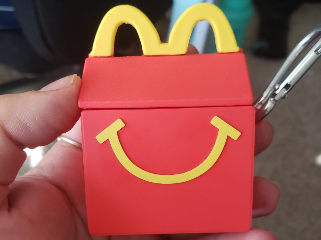holding an AirPods case shaped like a Happy Meal