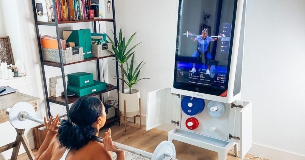 woman lifting weights in front of fitness mirror