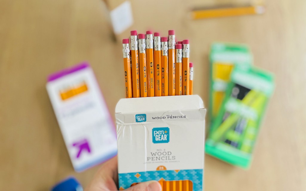 hand holding a box of pen and gear wood pencils