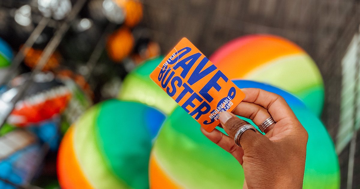 hand holding dave and busters powercard over rainbow colored balls