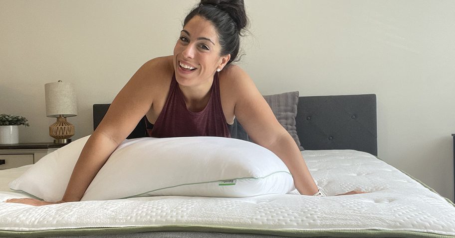 woman kneeling on bare mattress in bedroom