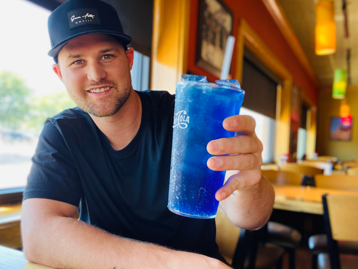 man holding blue raspberry and blackberry drink