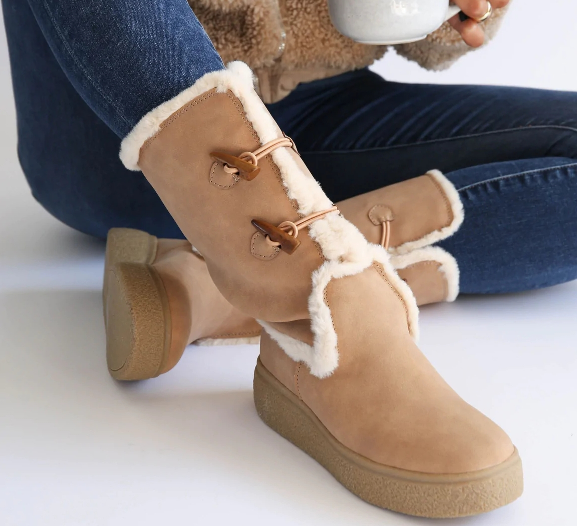 person sitting on the ground and wearing a tall pair of Rocket Dog boots with a sherpa lining