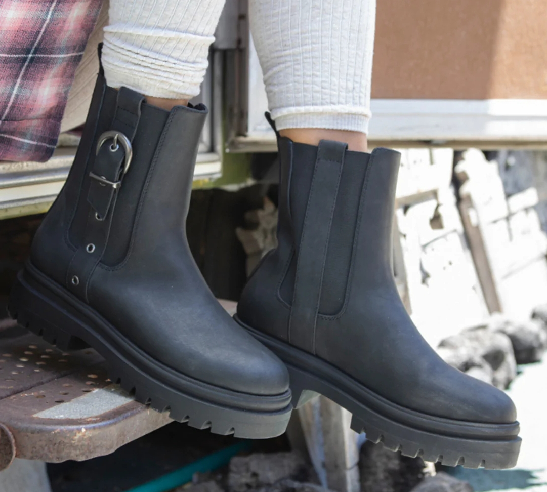 person sitting on the step of a camper and wearing leggings and a black pair of boots