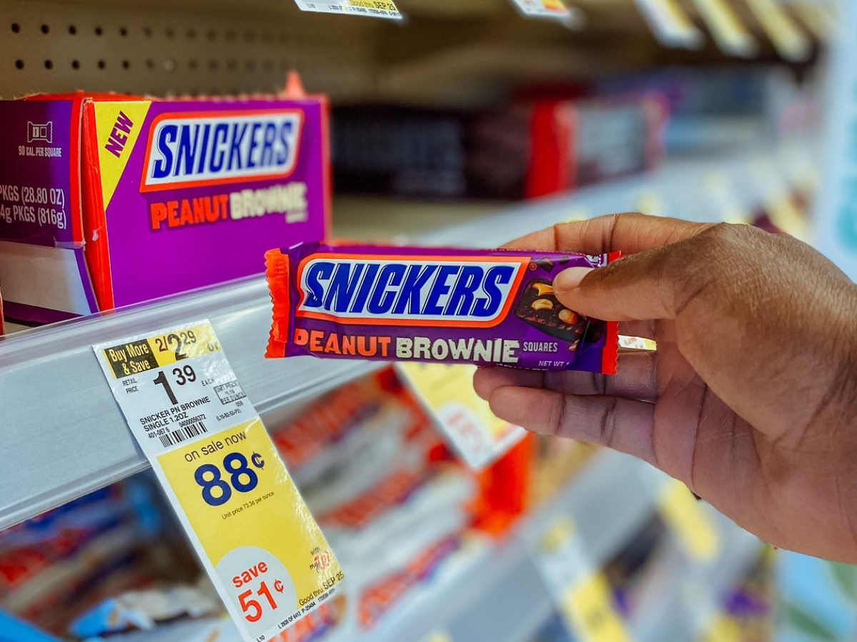 hand holding snickers peanut brownie candy bar